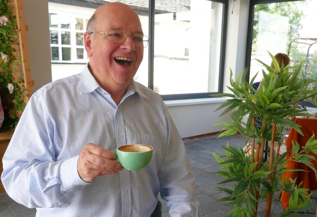 William laughing with a cup of coffee